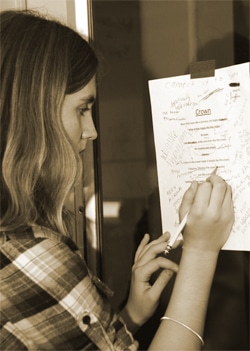 A student writing on the guide taped to the wall
