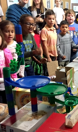Students watching a structure designed for marble races