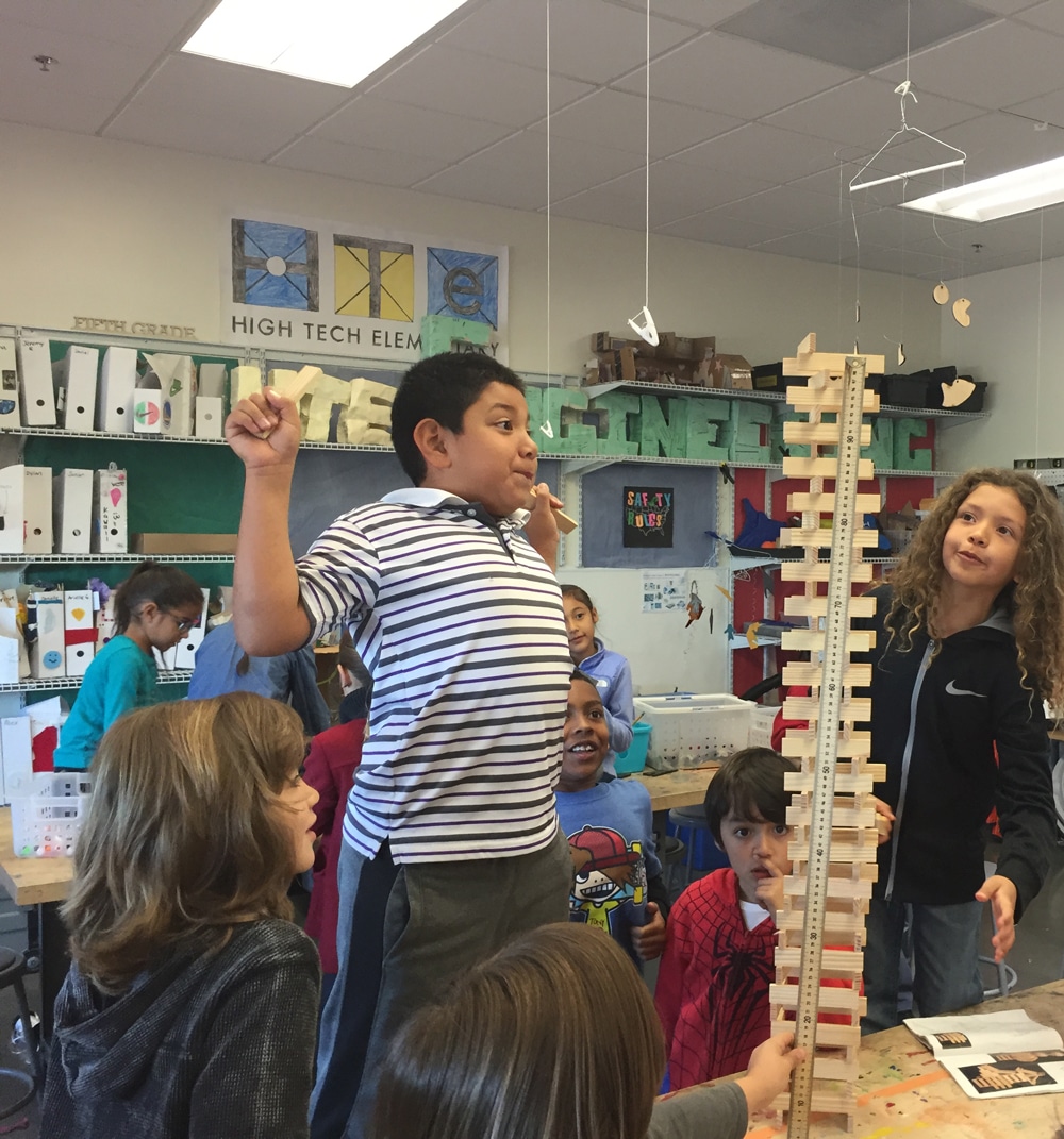 A young student next to a wood block tower