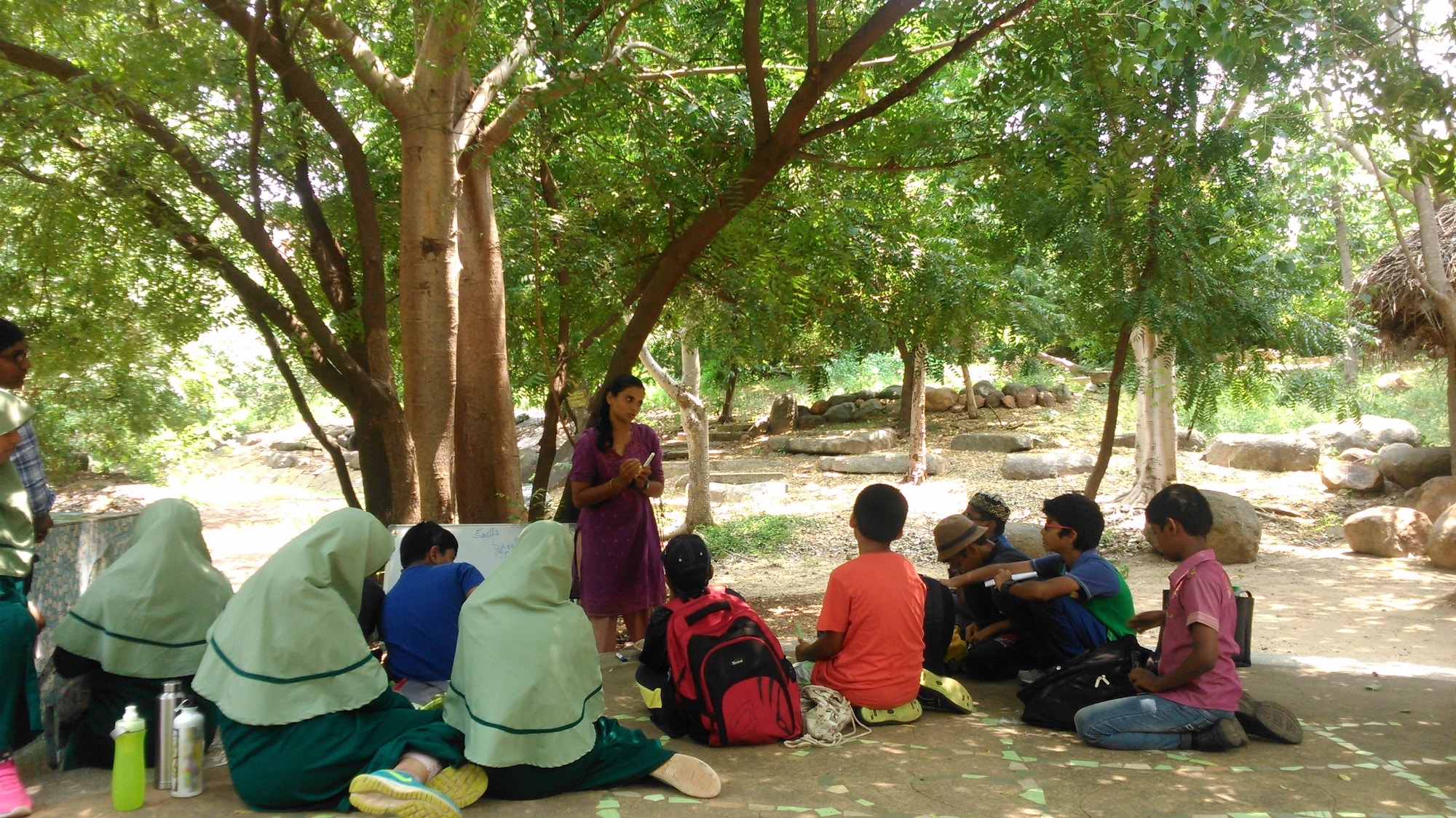 Teacher talking to students under a tree