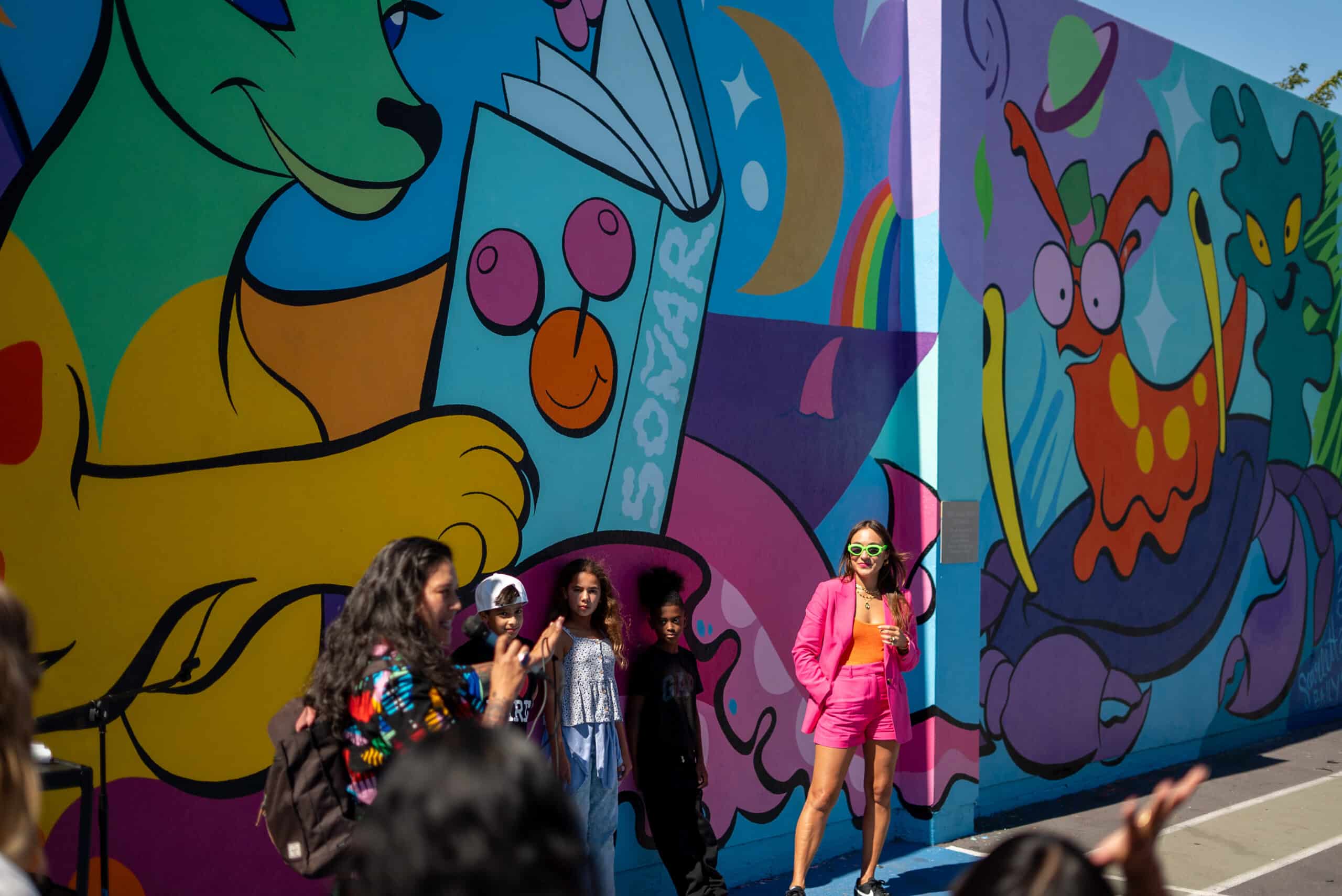Nuvia Ruland, Scarlett Baily, and elementary school students in front of the High Tech Elementary Explorer mural
