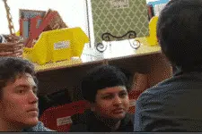 A group of people sitting and talking in a room with bookshelves in the background.