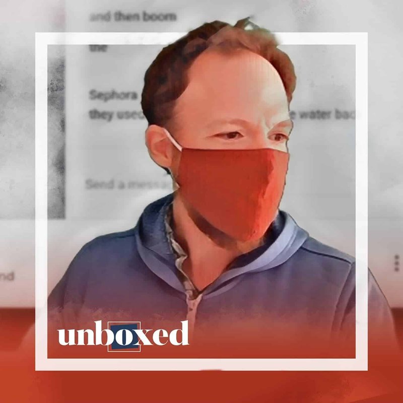 A person wearing a red mask and blue jacket is in focus against a blurred background, reminiscent of the Cheltenham PBL Experiment. The word unboxed is displayed in the lower left corner, capturing the essence of assembling the team.