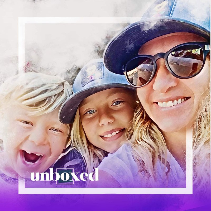 A smiling woman wearing sunglasses poses with two kids, all sporting caps. The frame has a white border, and unboxed is written in white and purple at the bottom. The background has a watercolor effect, capturing the essence of playful exploration akin to Student Led Conferences.
