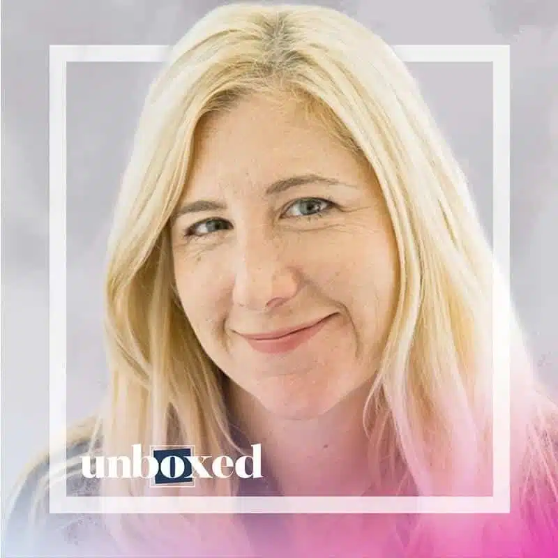 Laura McBain, with her long blonde hair, smiles gently against a soft gray background with a subtle pink hue in the bottom right corner. The frame reads unboxed near the bottom left, inviting viewers to explore deeper learning and uncover new origins.