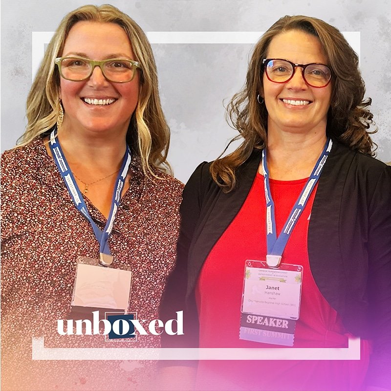 Two women smiling at a conference, wearing glasses and name badges. One, with long blonde hair and a patterned blouse, exudes teacher empowerment; the other, with long brunette hair in a black jacket over a red top, radiates improvement. A label reads “unboxed” with a colorful gradient frame.