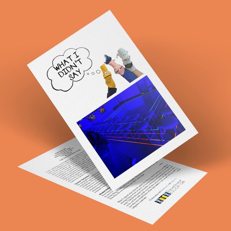 A greeting card on an orange background features Finger Puppets from the Puppet Project with speech bubbles saying WHAT I DIDNT SAY, accompanied by a blue-toned image of a geometric structure. The card includes printed text and a small logo on the bottom right.