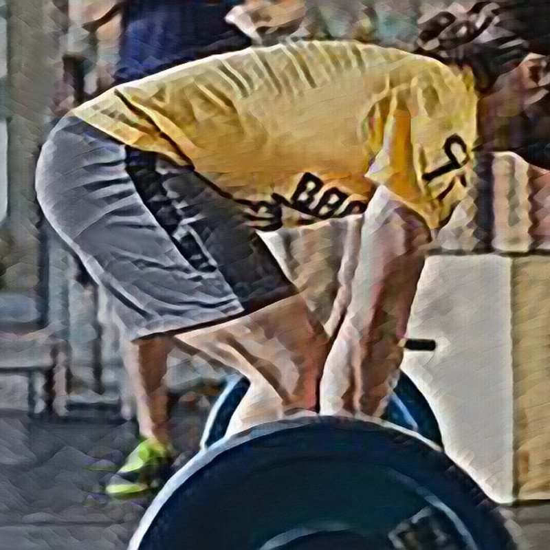 A person in a yellow shirt and gray shorts expertly projects their strength while performing a deadlift in the gym. With a focused stance gripping the barbell, they demonstrate technique akin to teaching skills, as gym equipment looms in the background.