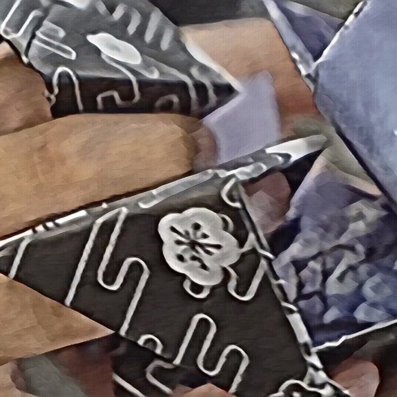 Close-up of intricately folded origami paper cranes. The paper boasts a black and white pattern with floral and abstract designs. The cranes overlapping wings and sharp folds create a geometric appearance, inviting cycles of reflection in their delicate artistry.