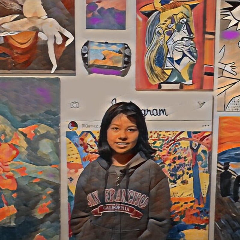 A young person stands smiling in front of a colorful wall full of abstract artwork, a testament to HTH Design Principles. The art features various styles and bold colors, creating a vibrant backdrop. The person wears a gray hoodie with San Francisco California printed on it.