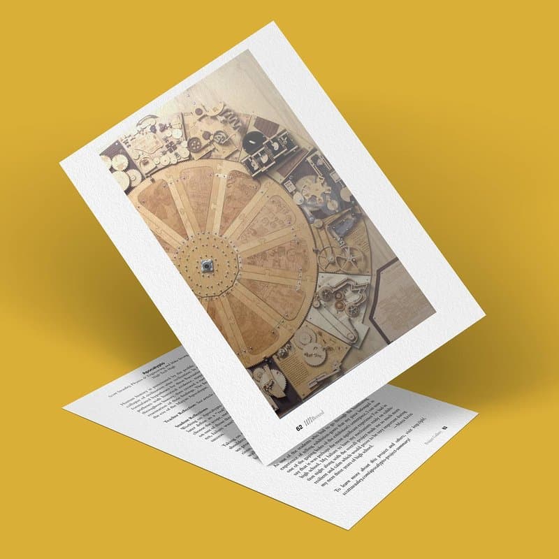 A vintage-style illustration of a circular diagram with intricate details is printed on a piece of paper resting on top of a document with text. The papers are on a solid yellow background.
