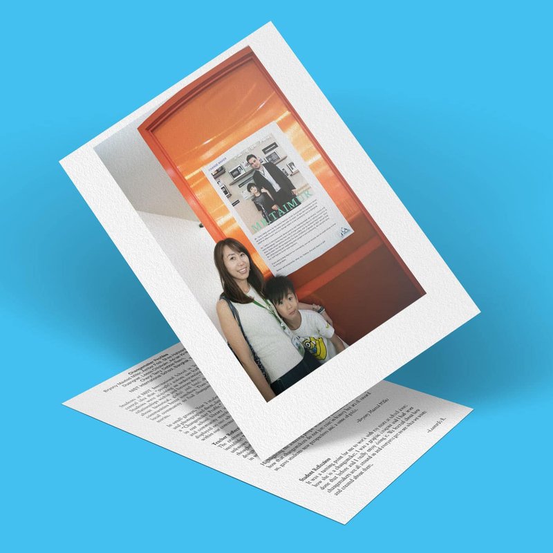 A woman and a child pose for a photo in front of a wall adorned with a poster showcasing profiles and images. The picture, set against a blue background, overlaps a sheet of paper with text, highlighting their roles as emerging changemakers.