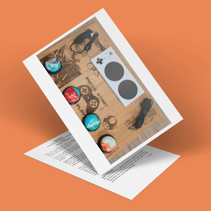 A white game controller with large black buttons is displayed alongside colorful button caps. The background has a wooden design with gaming icons. A cable is included, and a sheet with text is partially visible beneath.