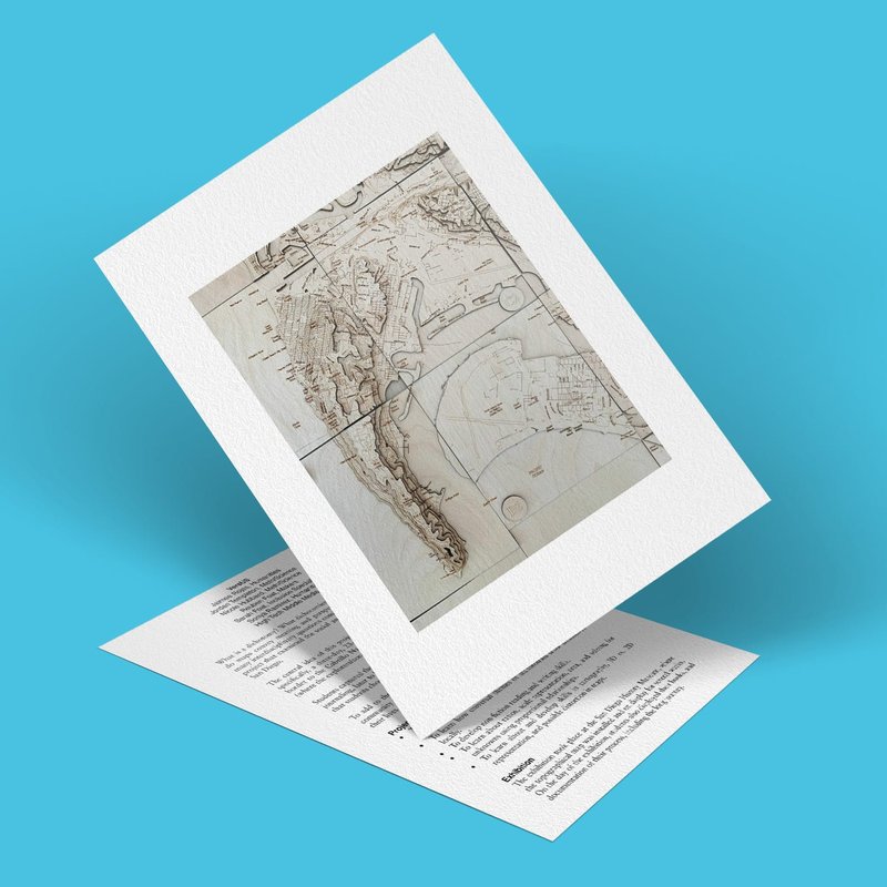A vintage map displayed on a folded card with a textured white border. The card is propped open against a blue background, revealing text printed on the inside.