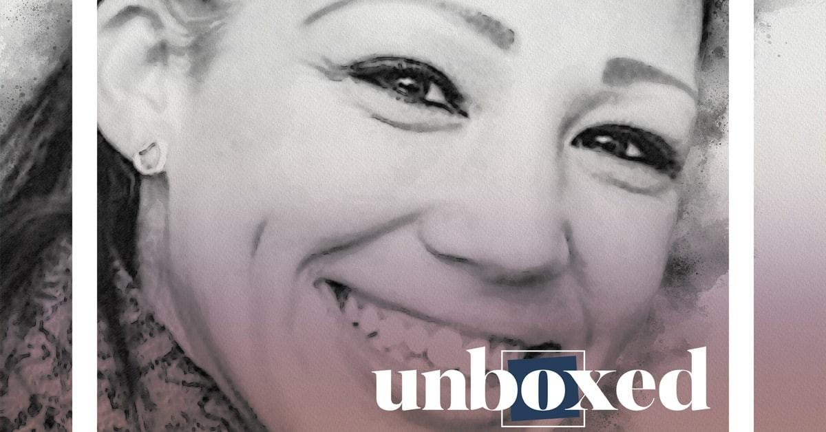 Portrait of a smiling person with long hair, featuring bold eyebrows and small earrings. The image is in a monochrome style with a purple tint, reminiscent of New York City Schools innovative spirit. The word unboxed is placed at the bottom.