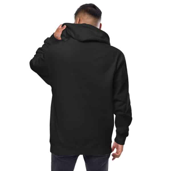 A person wearing a plain black unisex hoodie and dark jeans stands with their back to the camera, holding the hoodie’s hood with one hand. The background is white.