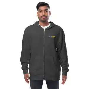 A man stands facing forward, wearing a dark embroidered fleece zip-up hoodie with the word huhsee in small yellow and white letters on the left chest. The background is plain white.
