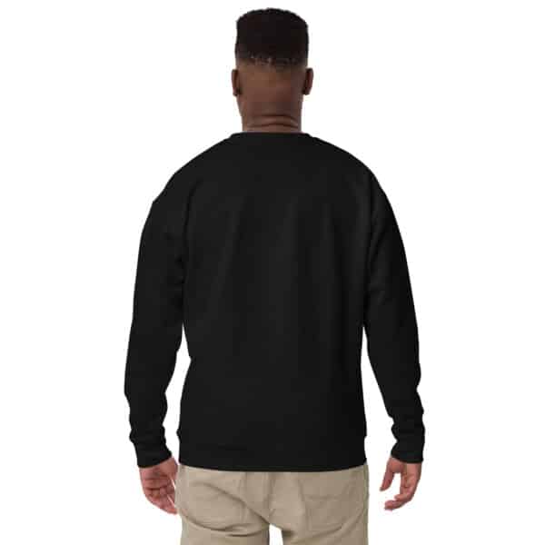 A person is standing with their back to the camera, wearing a unisex crew neck sweatshirt with a subtle white logo and light beige pants against a white background.