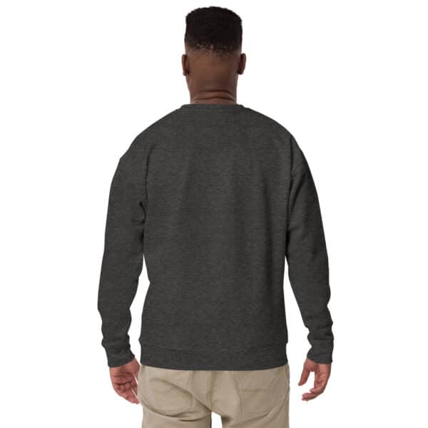 A person wearing a dark gray, crew neck sweatshirt and light beige pants stands facing away from the camera against a plain white background.
