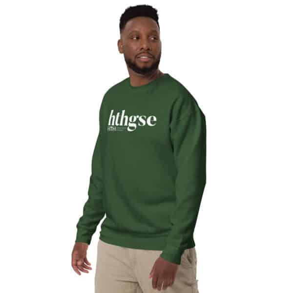 A man with short hair and a beard wears a dark green Unisex Crew Neck Sweatshirt featuring the white hthgse logo on the front. He stands, looking slightly to the side in light-colored pants against a plain white background.