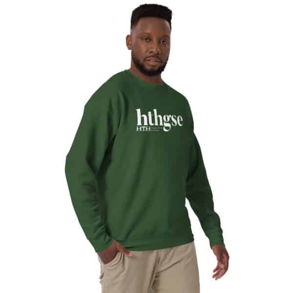 A man in a green crew neck unisex sweatshirt with a white logo reading hthgse and F I T H stands against a plain white background, looking at the camera with one hand in his pocket.