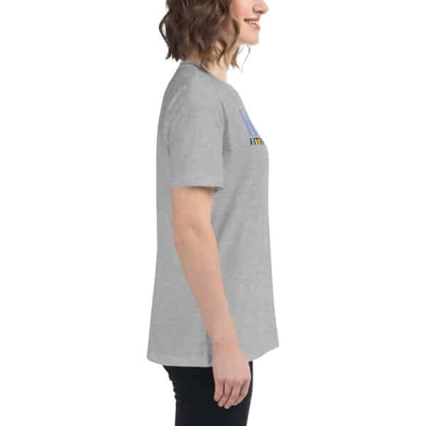Woman standing in profile, smiling in a women's relaxed fit t-shirt and black pants, against a plain white background.