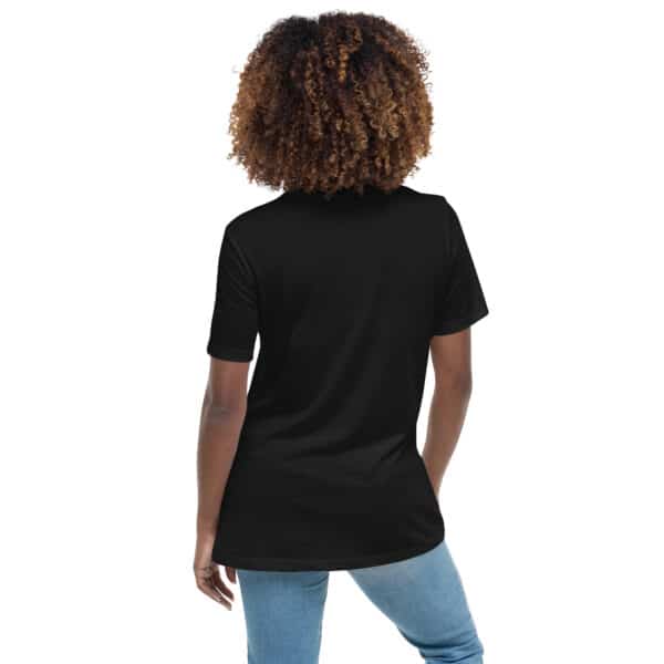 A person with curly hair is shown from behind, wearing a women's relaxed fit t-shirt with a white logo and light blue jeans, standing against a white background.