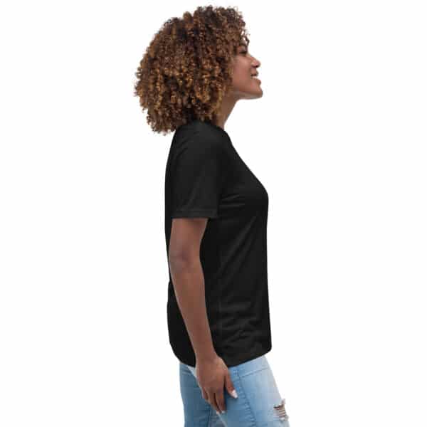 A woman with curly hair is standing in profile, smiling, wearing a Women's Relaxed Fit T-Shirt and light blue ripped jeans against a plain white background.