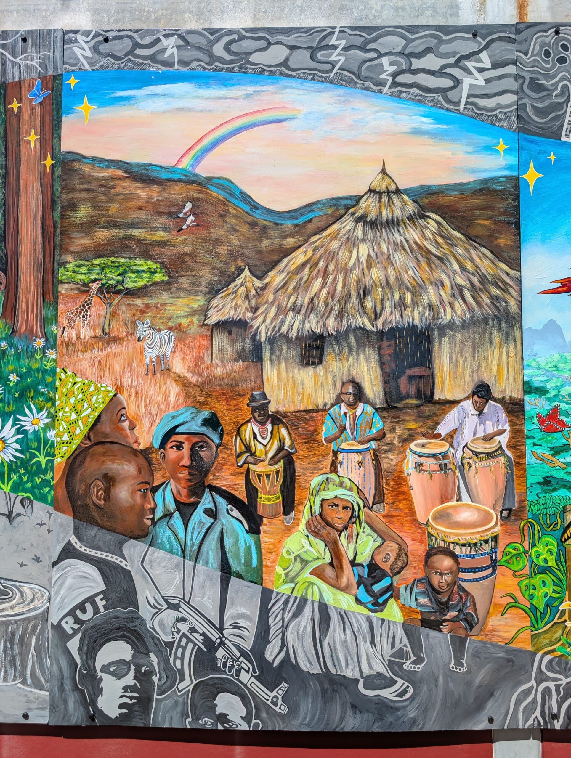 A colorful Imagine Mural shows African villagers near thatched huts with a rainbow overhead. People play drums, converse, and wear traditional clothing. Wildlife, trees, and gray portraits border the Honor A Life rural scene.