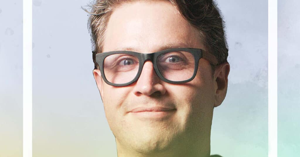 A person with short brown hair and glasses smiles slightly while looking at the camera, set against a soft gradient background—reflecting the spirit of the Honor A Life project.