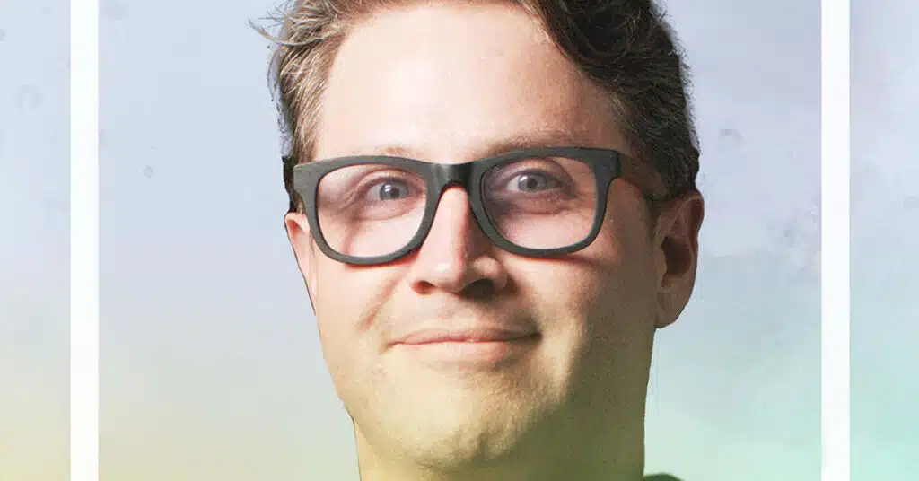 A person with short brown hair and glasses smiles slightly while looking at the camera, set against a soft gradient background—reflecting the spirit of the Honor A Life project.