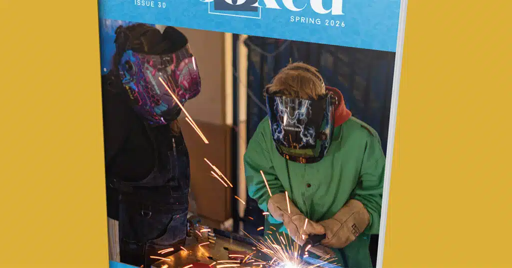 Two people wearing colorful protective welding helmets and gloves work together, producing sparks, on the cover of a magazine titled Red, Issue 30, Spring 2026.